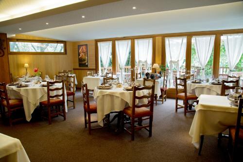 un restaurante con mesas y sillas blancas y ventanas en Auberge Saint Fleuret, en Estaing