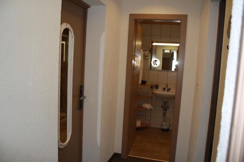 un corridoio che conduce a un bagno con lavandino e specchio di Hotel de la Gare a Monthey