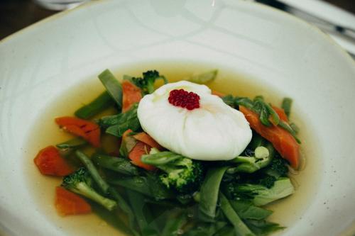 a plate of food with vegetables and a poached egg on top at ICON Embassy in Madrid