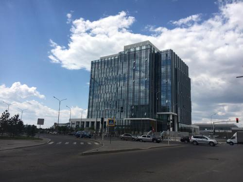 a large glass building with cars parked in front of it at Eco Apart Hotel Astana in Astana