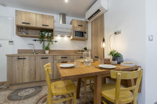 a kitchen with a wooden table and yellow chairs at Valbonne Flat in Valbonne