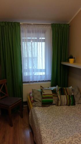 a bedroom with a bed and a window with green curtains at Apartament przy plaży in Kuźnica