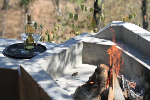 a table with two glasses of wine next to a fire at Tantebane Game Ranch in Tantebane