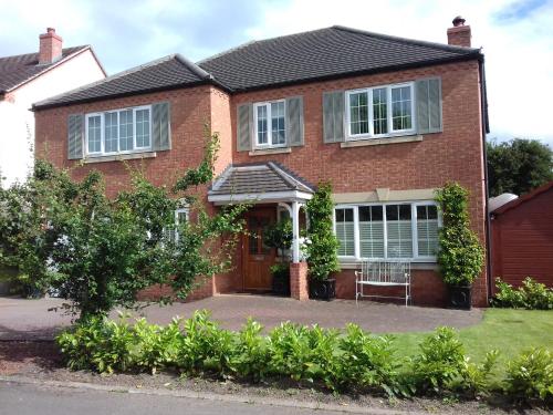 a red brick house with a porch at Harlequin B&B Ledbury in Ledbury