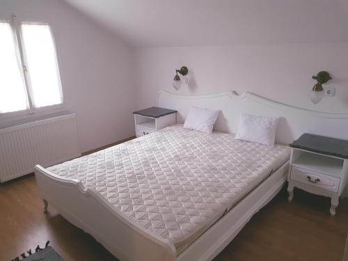 a bedroom with a white bed and a window at Favilla Apartmanok2 in Bogács
