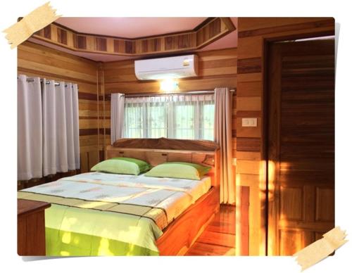 a bedroom with a bed in a room with a window at Magmai Riverside in Tak