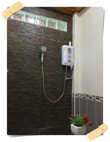 a shower with a hose attached to a brick wall at Magmai Riverside in Tak