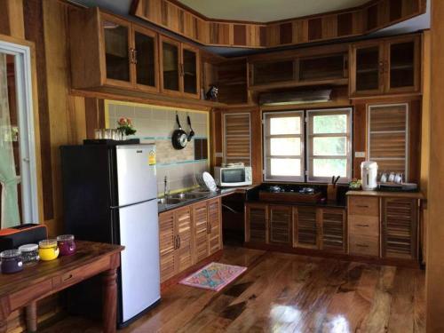 een keuken met een witte koelkast en houten kasten bij Magmai Riverside in Tak