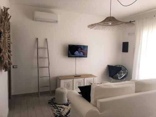 a living room with a white couch and a tv on a wall at Residence Mar Mediterraneo in Quartu SantʼElena