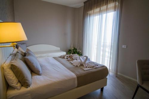a bedroom with a bed with a lamp and a window at Hotel Lady Mary in Milano Marittima