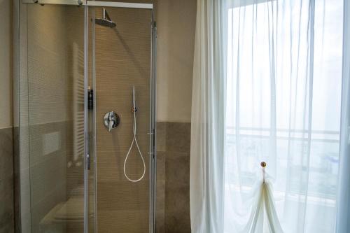 a shower with a glass door next to a window at Hotel Lady Mary in Milano Marittima