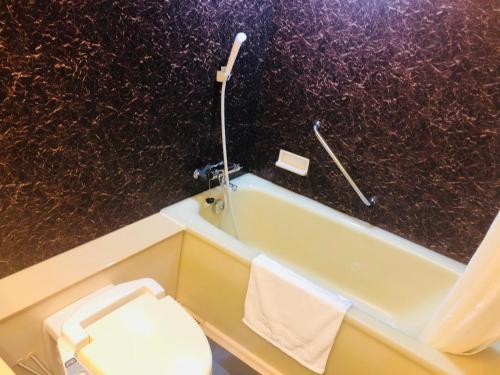 a bathroom with a toilet and a bath tub at Hotel Route-Inn Ageo in Ageo