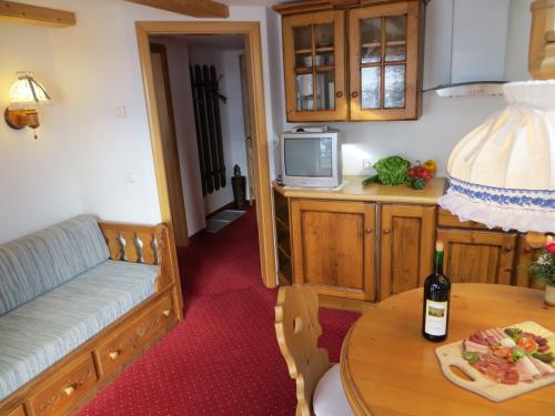 a living room with a couch and a table with a bottle of wine at Gästehaus am Berg in Hirschegg