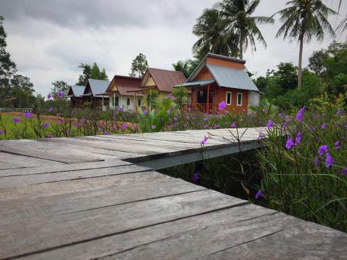 a wooden walkway in front of a group of houses at Baan Thung Home Stay in Prasat