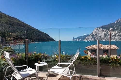 a patio with chairs and a view of the water at Hotel Lago Di Garda in Nago-Torbole