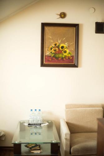 a living room with a table and a painting of flowers at Lodownia in Szydłowiec