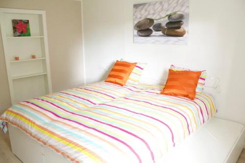 a bed with colorful striped sheets in a room at La Lunadeléo in Wépion