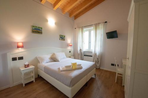una camera da letto con un grande letto bianco e una finestra di Le Bignele a Marano di Valpolicella