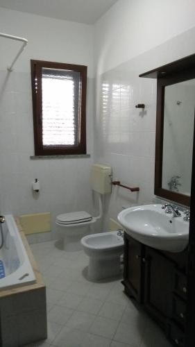 a bathroom with a toilet and a sink and a mirror at Casa Vacanze Leo in Acquarica del Capo