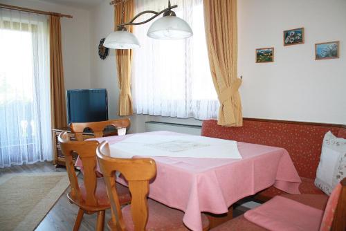 a dining room with a pink table and chairs at Haus Vierjahreszeiten in Reit im Winkl