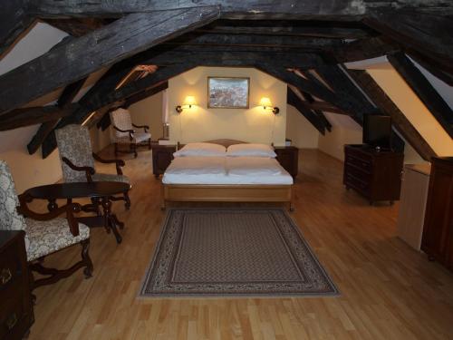 Habitación en el ático con cama, mesa y sillas en Hotel King George en Praga