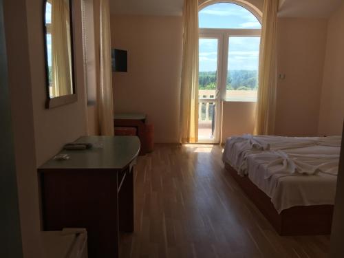 a bedroom with a bed and a large window at Arkadia Guest House in Primorsko