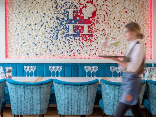 a woman walking past a table with wine glasses at HYDE Hotel in Galway