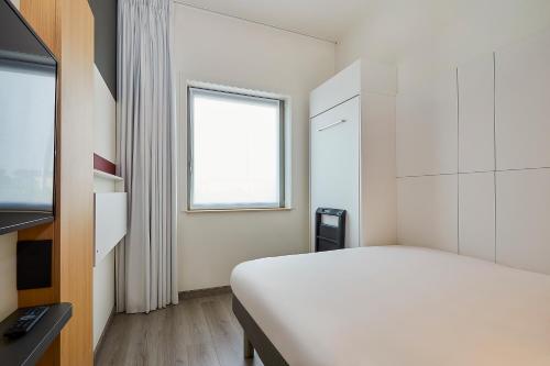 a white room with a bed and a window at ibis budget Oostende Airport in Ostend