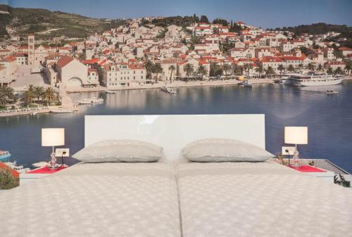 a bed with two pillows and a view of a city at Apartments Majić in Hvar
