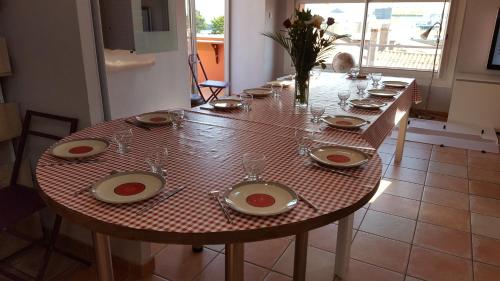 een lange houten tafel met borden en wijnglazen erop bij Villa du Quai in Les Sables-dʼOlonne