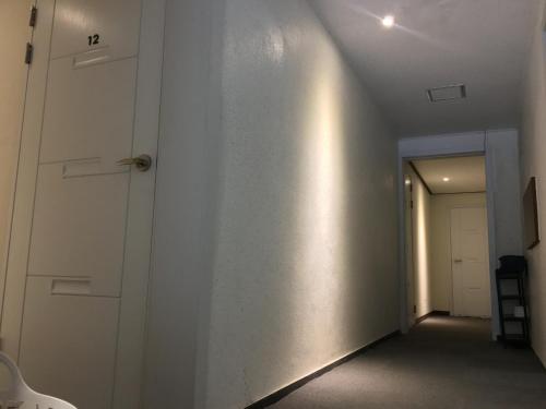 a hallway with a white wall and a door at Take 1 Guesthouse Hongdae in Seoul