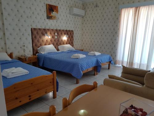 um quarto de hotel com duas camas e um sofá em Hotel Apollon em Rio