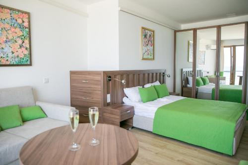 a bedroom with a bed and a couch and two wine glasses on a table at Villa RK DeLuxe in Zatoka