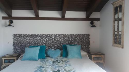 a bedroom with a bed with blue pillows at Lagar II con Jacuzzi in Curiel de Duero
