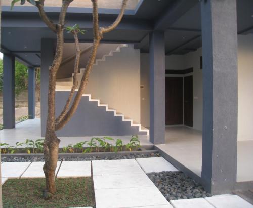 a palm tree in front of a building with a staircase at Cafe Alberto B and B in Senggigi 
