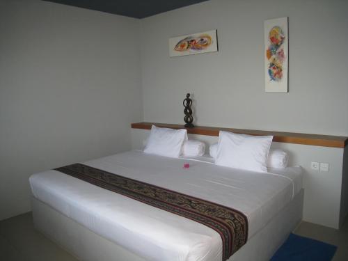 een slaapkamer met een wit bed met witte lakens en kussens bij Cafe Alberto B and B in Senggigi 