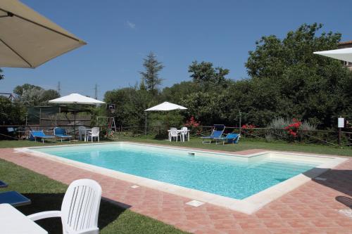 una piscina con sillas, mesas y sombrillas en Agriturismo Le Stringaie, en Montepulciano Stazione