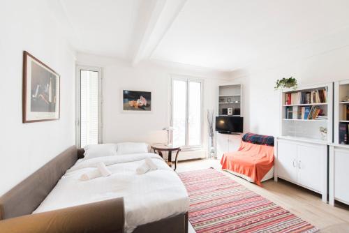 a white bedroom with a bed and a living room at Veeve - Contemporary in Balard in Paris
