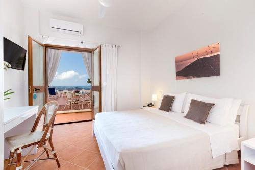 a bedroom with a bed and a desk and a balcony at Il Cefalo Hotel & Restaurant in Castellabate