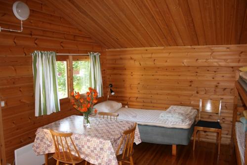 una habitación con una cama y una mesa en una cabaña en Borggården stugor, en Hultsfred