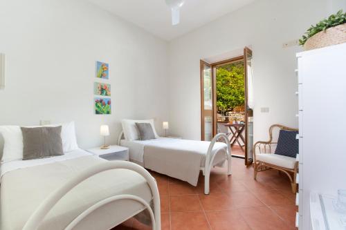 a white room with two beds and a chair at Il Cefalo Hotel & Restaurant in Castellabate