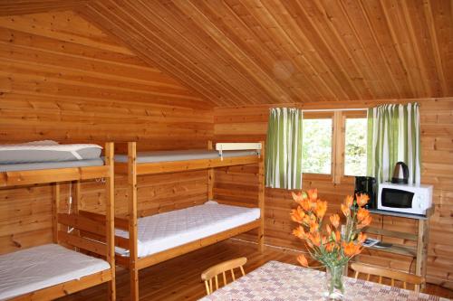 Cette cabane en rondins comprend des lits superposés et une table. dans l'établissement Borggården stugor, à Hultsfred