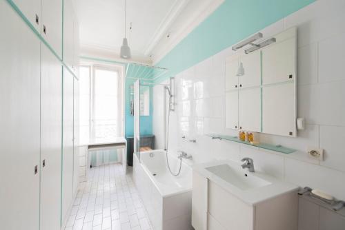 La salle de bains blanche est pourvue d'un lavabo et d'une baignoire. dans l'établissement Veeve - Saint-Germain des Prés Allure, à Paris