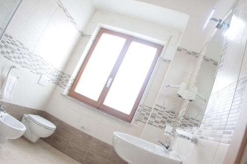 a bathroom with a toilet and a sink and a window at A'MANTIA HOTEL in Amantea