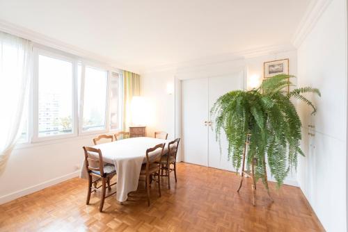 a dining room with a table and chairs and a plant at Veeve - Apartment near Pont de Grenelle in Paris