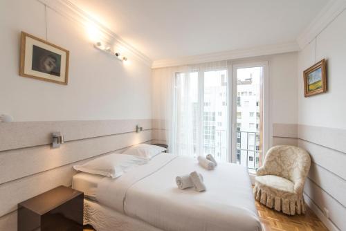 a bedroom with a bed and a chair and a window at Veeve - Apartment near Pont de Grenelle in Paris