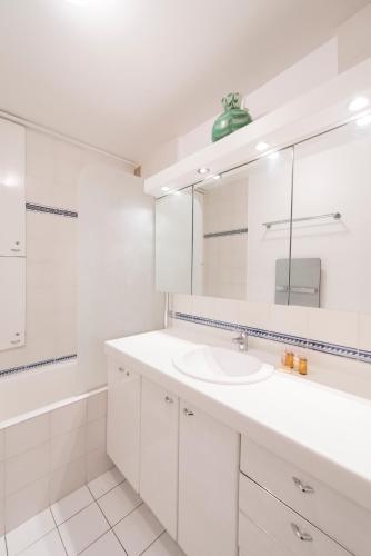 une salle de bain blanche avec un lavabo et un miroir dans l'établissement Veeve - Apartment near Pont de Grenelle, à Paris