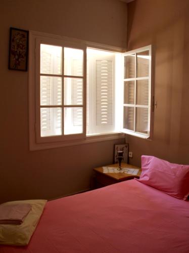 a bedroom with a bed and two windows at Family house in Kalamata