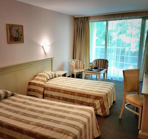 Habitación de hotel con 2 camas, mesa y sillas en Hotel & SPA Otdih en Kavarna