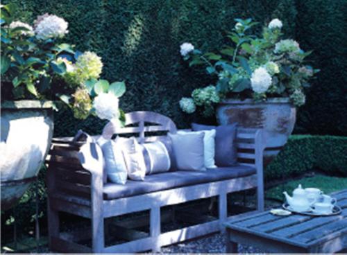 a blue bench with pillows on it in a garden at Huka Lodge in Taupo
